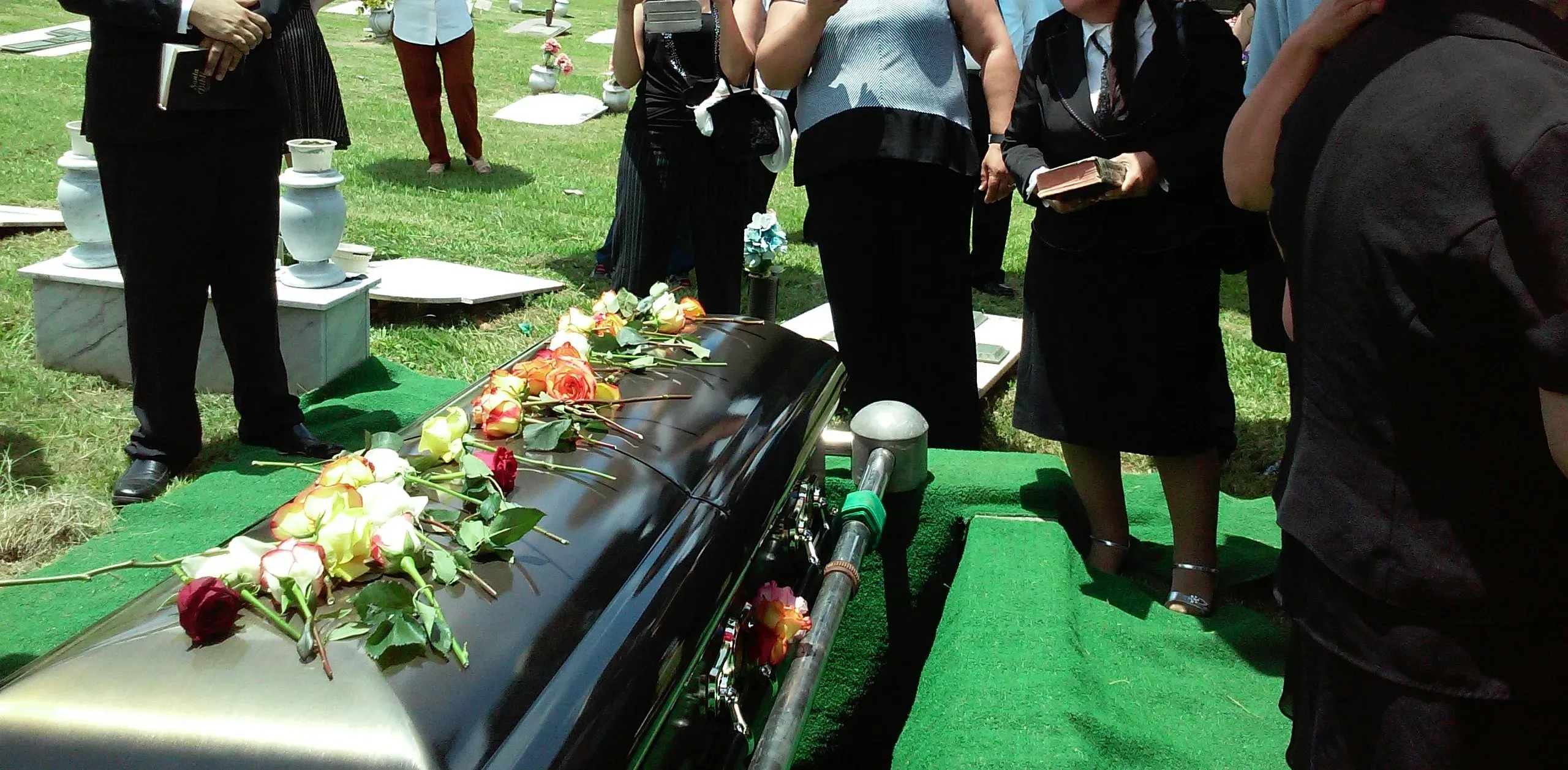 Cérémonie d'inhumation d'un cercueil recouvert de roses au cimetière